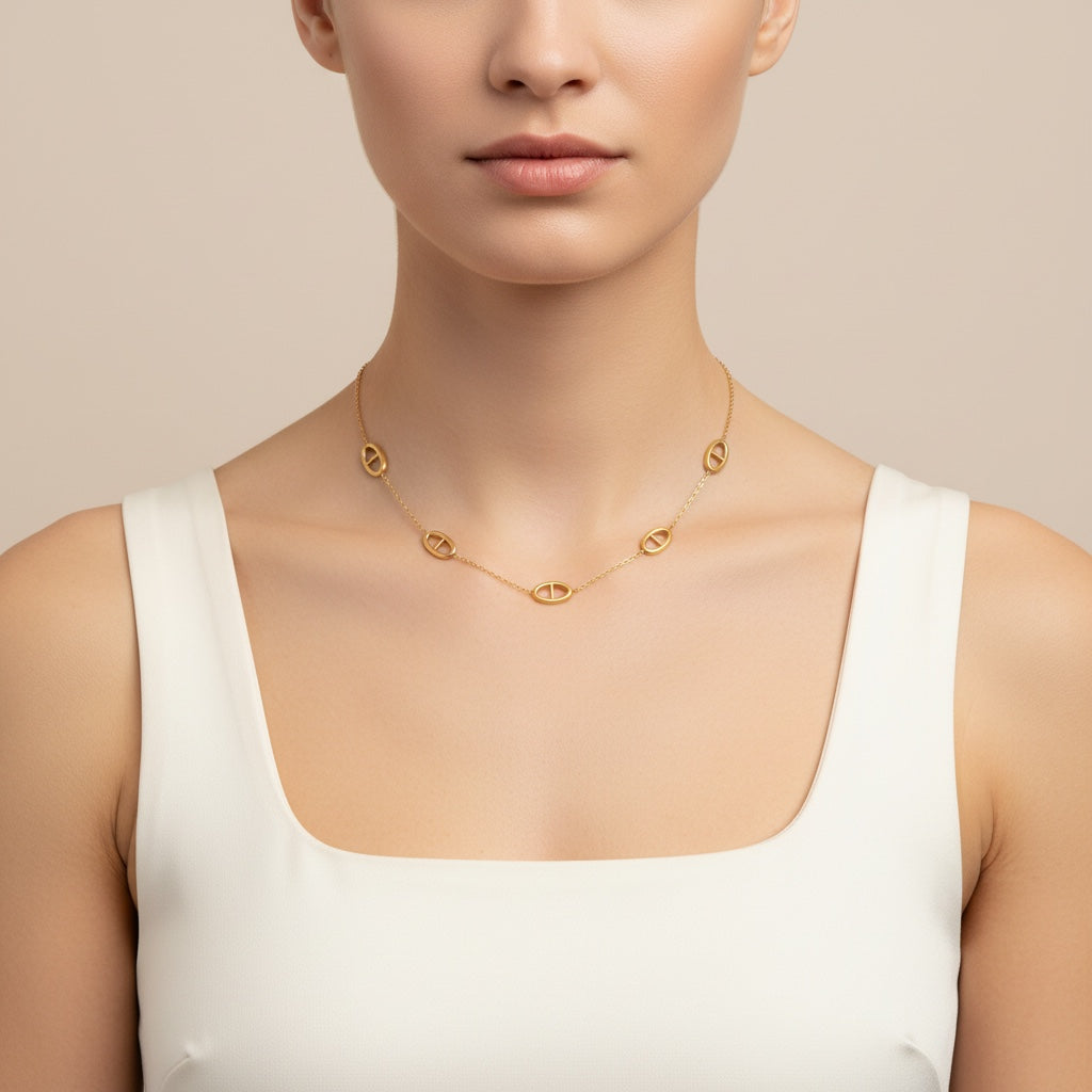 Collier TINA de Margeli, orné de pendentifs élégants, porté sur un fond neutre, mettant en valeur le design fin et sophistiqué.