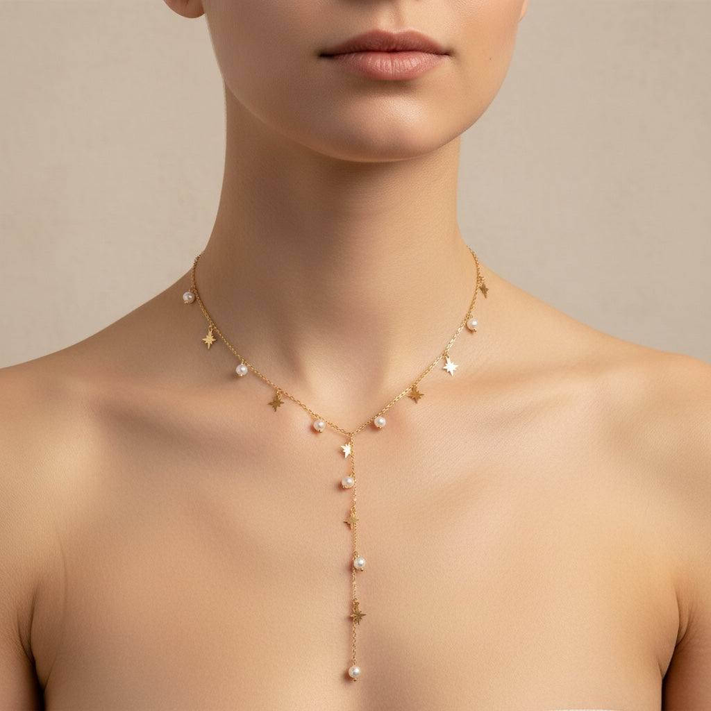 Collier ELODIE de Margeli, en métal avec pendentif délicat, porté sur une main avec bijoux en arrière-plan.